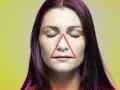 Frauenkopf mit geschlossenen Augen, auf dessen Nase und Mund ein rotes Dreieck liegt. Ein Pickel im Todesdreieck im Gesicht kann gefährlich sein.