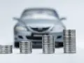Monete in crescita davanti a un'auto sfocata, simbolo di speranza per l'abolizione superbollo e un futuro più sereno per gli automobilisti.