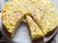 Una fetta di torta di patate filante, dorata e profumata al rosmarino, pronta per essere gustata.