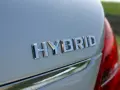 Chromowane napisy "HYBRID" na białym nadwoziu samochodu. To nowoczesny hybrydowy pojazd elektryczny, gotowy na ekologiczną podróż.