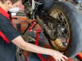 Meccanico lubrifica la catena di una moto. La pulizia catena moto ogni quanti km è fondamentale per la sua durata.