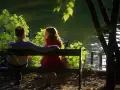 Para siedzi na ławce nad jeziorem. Ona patrzy w bok z nadzieją, on w dal. Obraz ukazuje, jak nieodwzajemniona miłość może wpłynąć na człowieka.
