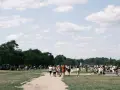 Menschen spazieren an einem sonnigen Pfingstmontag in Berlin durch eine grüne Parklandschaft.
