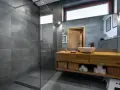 Salle de bain moderne avec douche à l'italienne, carrelage gris, meuble en bois et vasque. Le pose carrelage douche italienne est impeccable.