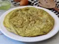 Frittata di carciofi dorata e soffice su un piatto bianco, pronta per essere gustata.