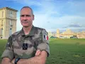 Un officier français, P. Schill, pose devant un bâtiment historique. Comment retrouver un officier ? Il suffit de regarder son uniforme et son insigne.