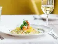 En elegant tallrik med saffransrisotto, toppad med en saftig räka och citrusklyftor. Ett glas vitt vin till saffransrisotto fulländar denna läckra måltid.