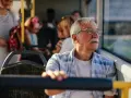 Starszy pan w okularach podróżuje autobusem, ciesząc się darmową komunikacją miejską.