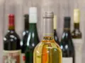 Butelki z winem na tle drewnianej ściany. Zastanawiasz się, ile alkoholu można wziąć do Norwegii samolotem?