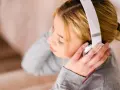 Dziewczyna w słuchawkach, skupiona, jakby robiła test na słuch muzyczny.