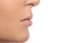 Primer plano de la nariz y los labios de una persona, mostrando la textura de la piel y los filamentos sebáceos en la nariz.