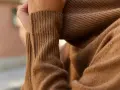 Mano acariciando un suave tejido de kashmir color camel.