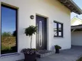 Piante e fiori per abbellire ingresso esterno casa. Porta moderna con maniglia lunga, finestre e numero civico 28.