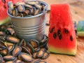 Kawałek arbuza z pestkami i wiaderko pełne pestek. Czy można jeść pestki arbuza? Tak, są jadalne i zdrowe!