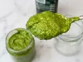 Un cucchiaio di fresco pesto genovese, pronto per essere messo in un vasetto. La ricetta pesto genovese frullatore è facile e veloce.