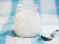 Słoiczek z domowym jogurtem, pełnym naturalnych probiotyków, czeka na łyżeczkę.