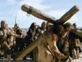 Scena z filmów chrześcijańskich: Jezus dźwigający krzyż, otoczony przez żołnierzy.