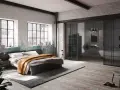 Ein gemütliches **Bett unter Fenster** mit industriellem Charme. Daneben ein offener Badbereich mit Wanne.