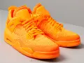 Un paio di scarpe Jordan 4 arancioni brillanti, con tomaia in maglia e dettagli iconici.