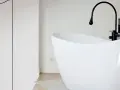 Baignoire îlot blanche au design moderne, avec robinetterie noire. Sa forme suggère une largeur baignoire standard, idéale pour un confort optimal.