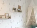 Habitaciones con papel pintado y pintura de patitos y flores. Un dosel de cama blanco cuelga sobre una cuna.