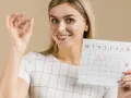 Kobieta pokazuje kalendarz z zaznaczonymi dniami, sugerując bolesną owulację.