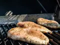 Trzy soczyste piersi z kurczaka na grilla, przyprawione ziołami, czekają na idealne upieczenie.