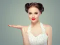 Kobieta w stylu pin-up z burzą loków i czerwoną szminką prezentuje dłoń.