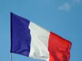 La bandera de Francia ondea con orgullo contra un cielo azul claro.