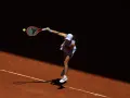 Tenisistka w skoku serwuje piłkę na korcie ziemnym podczas Roland Garros.