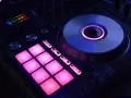 DJ kontroler z podświetlanymi na różowo padami i świecącym na niebiesko talerzem. Idealny do tworzenia muzyki, np. dubstep co to za gatunek?