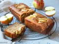 Saftiger Apfelkuchen mit Apfelmus-Note, dekoriert mit frischen Apfelscheiben. Daneben liegen Äpfel und ein Stück Kuchen.