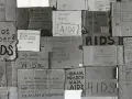 Złe ojciec, zniszczony przez AIDS, błaga o pomoc. Kartony z napisami "AIDS", "SOS", "Ratunku!" i prośbami o wsparcie.