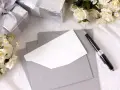 Eleganckie prezenty, bukiet róż i koperty z pustą kartką czekają na napisanie wyjątkowego psalm na ślub.