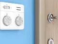 Termostato bianco su muro blu, parte di sistemi termoregolazione evoluti per un comfort ottimale. Manopole per impostare la temperatura.