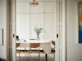 Comedor con mesa cubierta de mantel blanco, sillas de madera y un gran armario empotrado. El estilo ncs blanco aporta luminosidad.