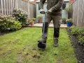 Gartenarbeit: Mit einem Werkzeug wird der Rasen aufgelockert, um ihn für besseres Wachstum vorzubereiten.