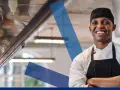 Chef sonriente con delantal negro, listo para servir. Conoce los derechos y obligaciones de un camarero.
