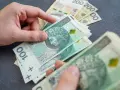 Dłonie liczą polskie banknoty 100 zł. Temat: zespół Aspergera a renta socjalna.