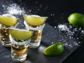 Złota tequila w kieliszkach z solą i limonką. Idealna na wieczór, by poczuć smak Meksyku. Jak pić? Szybko, z pasją!