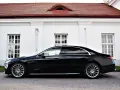Elegancki, czarny Mercedes S500 lśni na tle białej, zabytkowej fasady z czerwonym dachem.