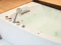 Bain bouillonnant avec jets d'eau et douchette chromée, prêt pour un moment de détente dans ce spa balnéo.