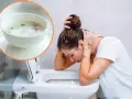 Kobieta z zatruciem pokarmowym pochyla się nad toaletą. W rogu widać miseczkę z ryżem i warzywami.