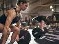 Kvinna fokuserar på ett helkroppspass 3 gånger i veckan, redo att lyfta skivstången i gymmet.