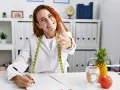 Dietetyczka z miarką, pisząca przy biurku, z ananasem i jabłkiem.