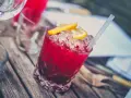 Orzeźwiające drinki z wódką dla pań, z lodem i plasterkami cytryny, na drewnianym stole.