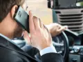 Biznesmen w garniturze rozmawia przez telefon, siedząc za kierownicą ciężarówki. To symbol odpowiedzialności spedytora.