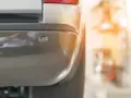 Zbliżenie na czujnik parkowania zamontowany w zderzaku samochodu. Montaż czujników parkowania ułatwia manewrowanie.