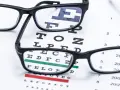 Okulary na tle tablicy Snellena do badania wzroku.
