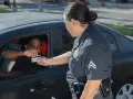 Policjantka odbiera prawo jazdy od kierowcy. Sytuacja sugeruje zatrzymanie prawa jazdy.